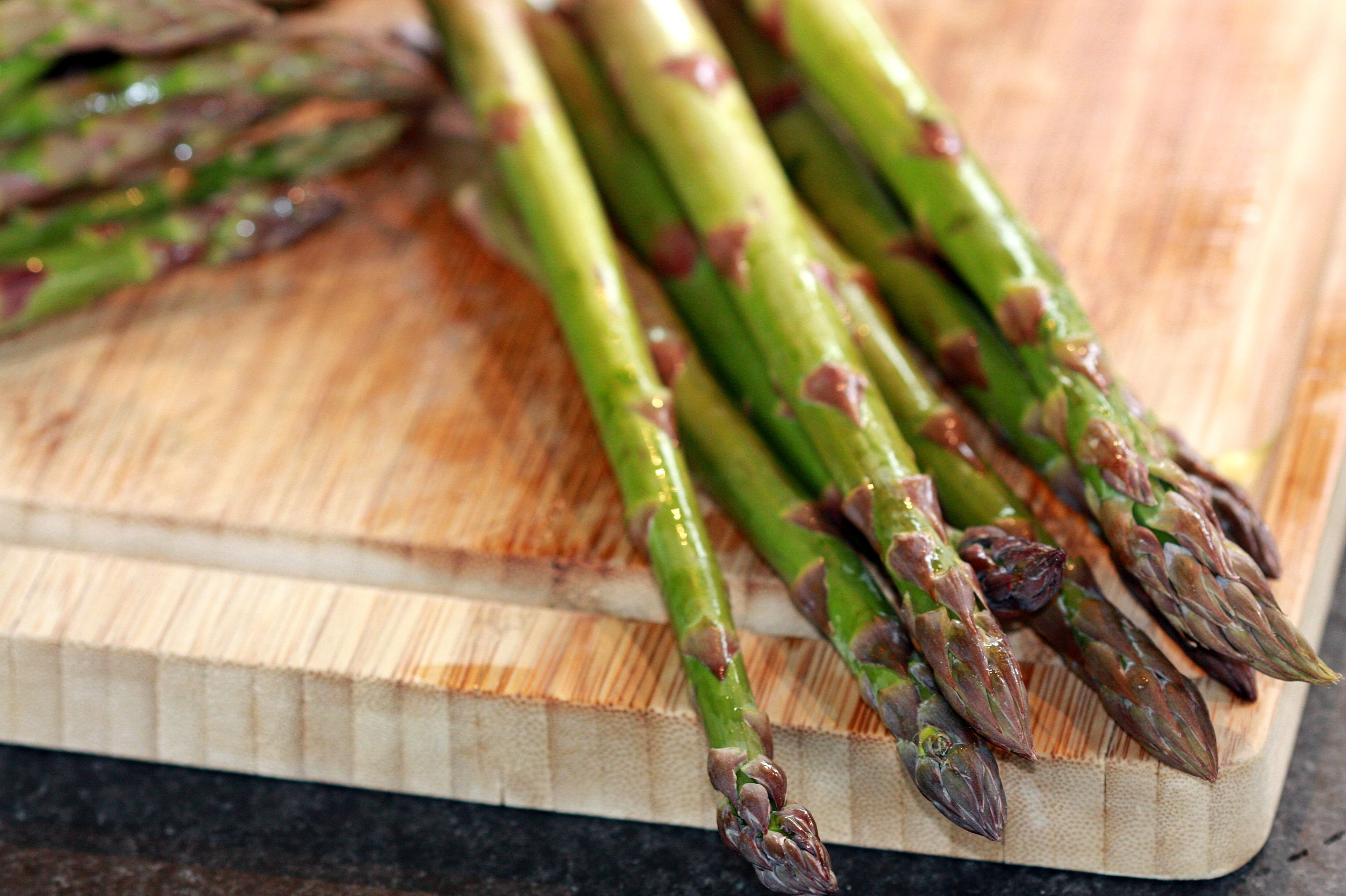Stalks of asparagus on a wooden cutting board. Asparagus is a great prebiotic which supports the growth of healthy gut microbiota