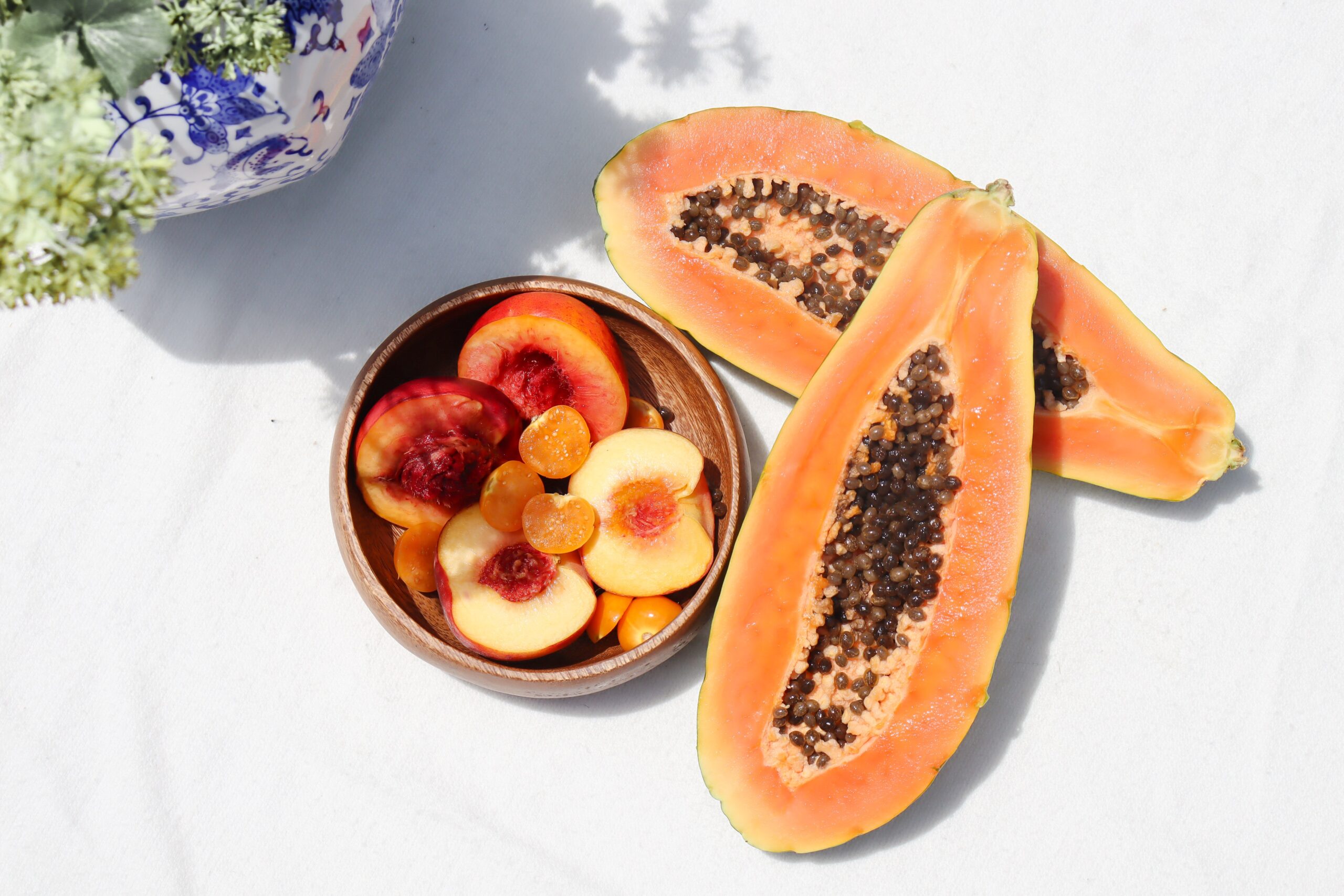 Papaya sliced in half next to a bowl of fruit. Some fruits are more diabetes-friendly than others.
